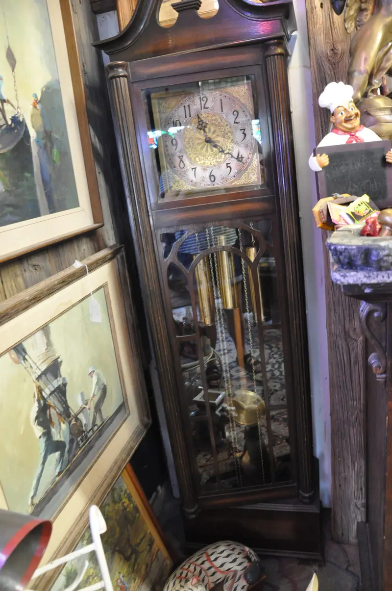 A grandfather clock beside framed paintings at Sample Studios